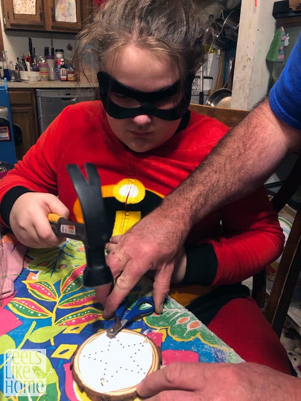 A girl in a superhero costume hammering in nails