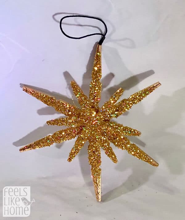 A finished clothespin snowflake covered in glitter