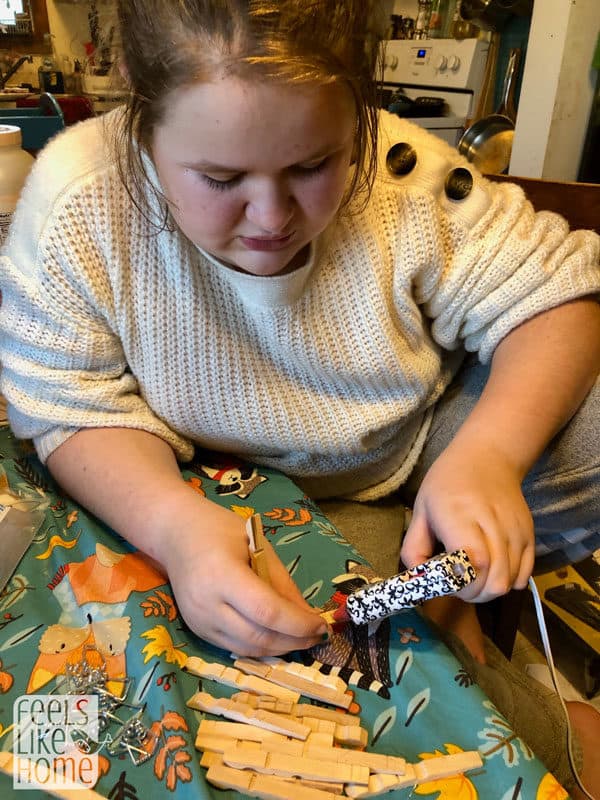 A girl gluing clothespins together