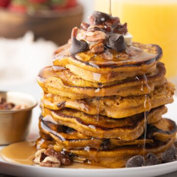 Pumpkin Spice pancakes piled high with maple syrup drizzle and pecans and chocolate chips