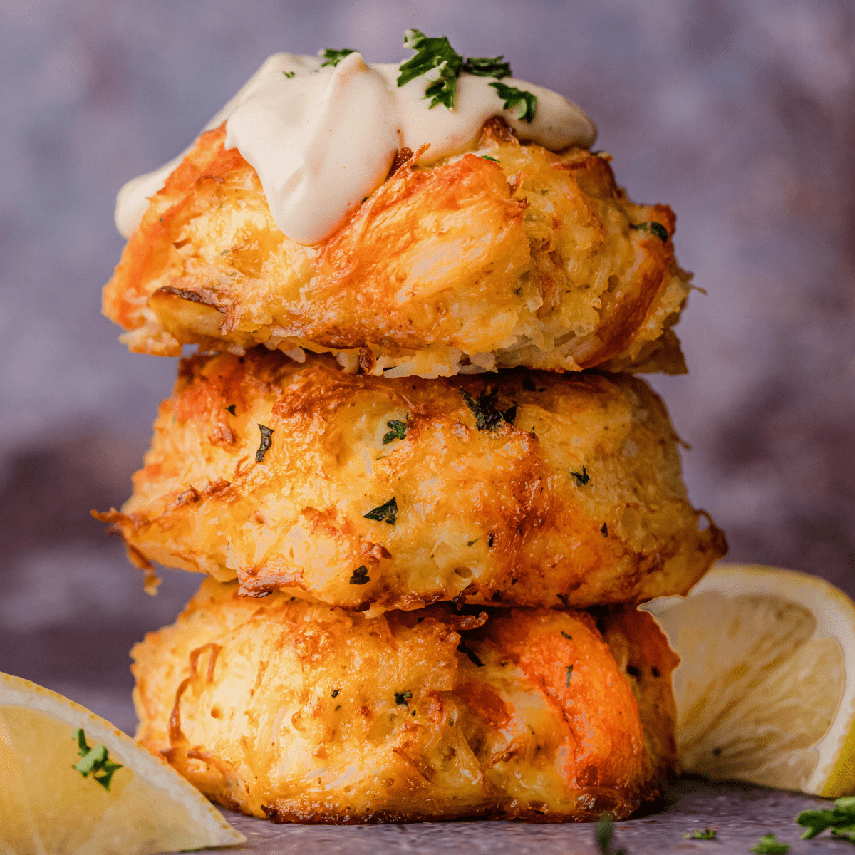 a stack of three crab cakes made with no filler and topped with cajun remoulade sauce
