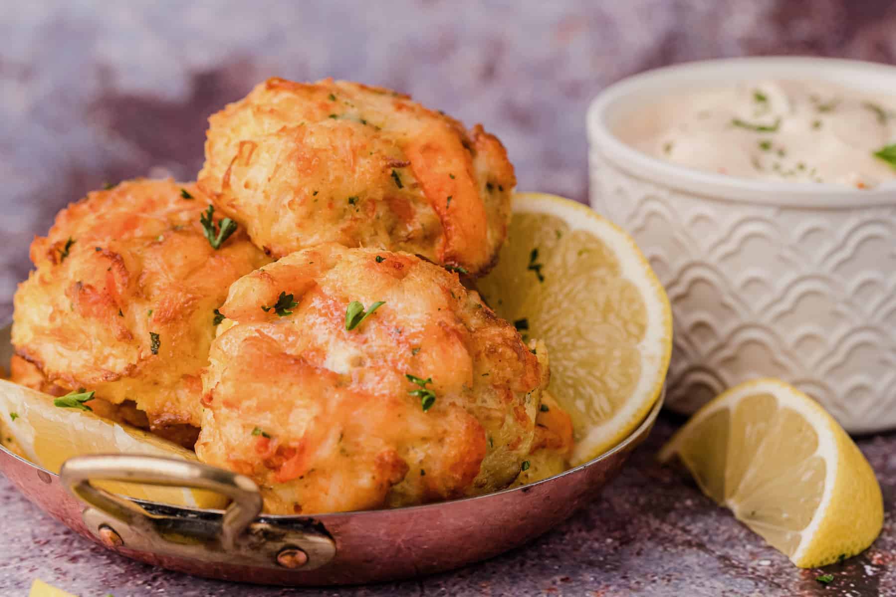 low carb crab cakes in a skillet with lemon wedges