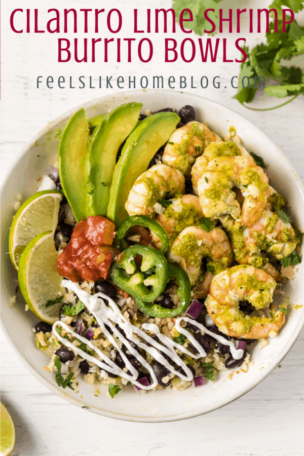 A burrito bowl with shrimp, avocado, black beans, jalapeños, salsa, onions, and a wedge of lime