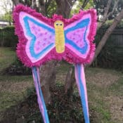 a butterfly piñata hanging in a tree