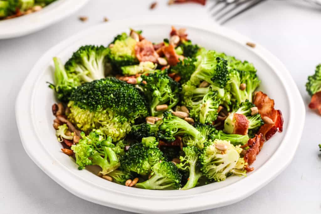 a bowl of broccoli salad in a white dish