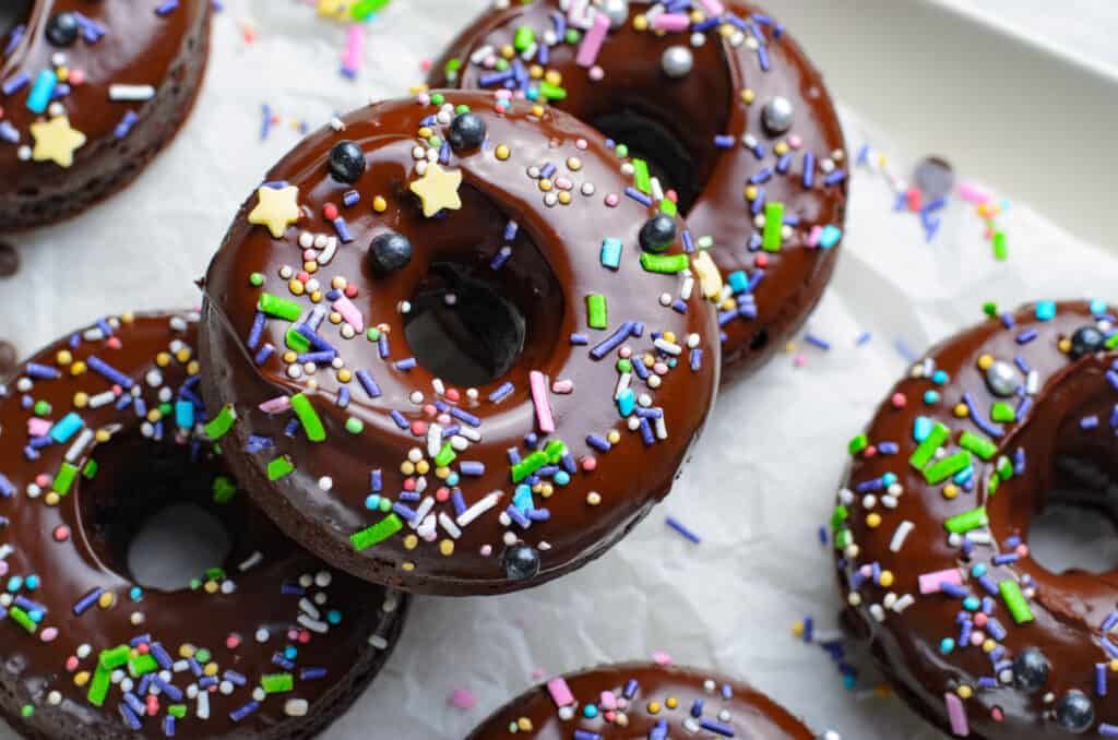 baked double chocolate donuts on parchment paper on a baking tray