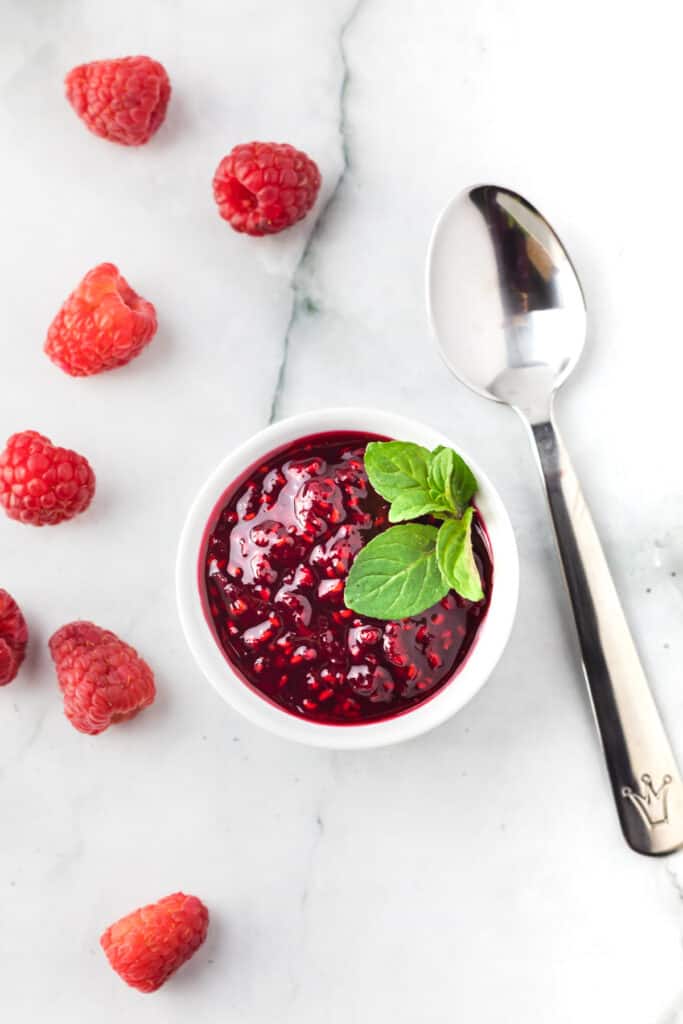a dish full of fresh raspberry sauce with a spoon