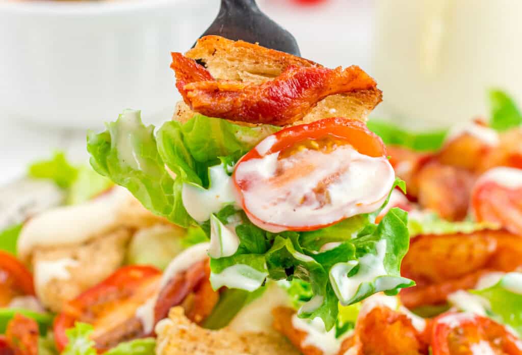 one bite of BLT salad with bacon, tomatoes, lettuce, and a bacon rye crouton