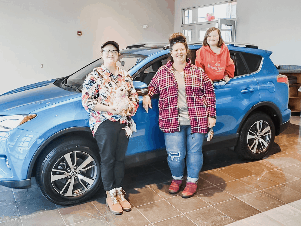 Tara Ziegmont and her daughters in front of a blue car