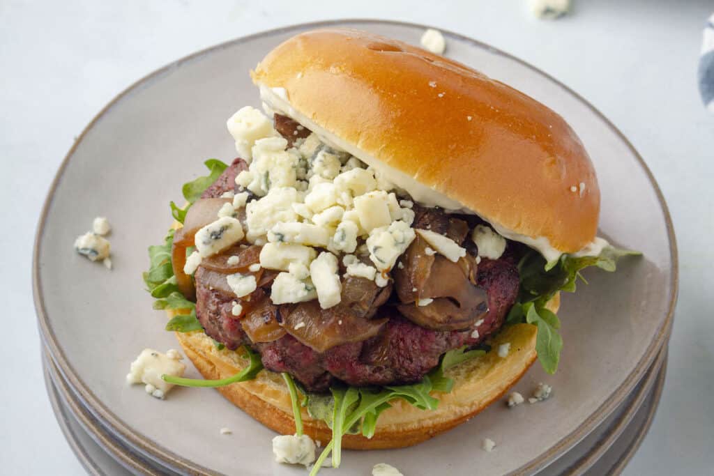 black and blue cheese burger on a white plate
