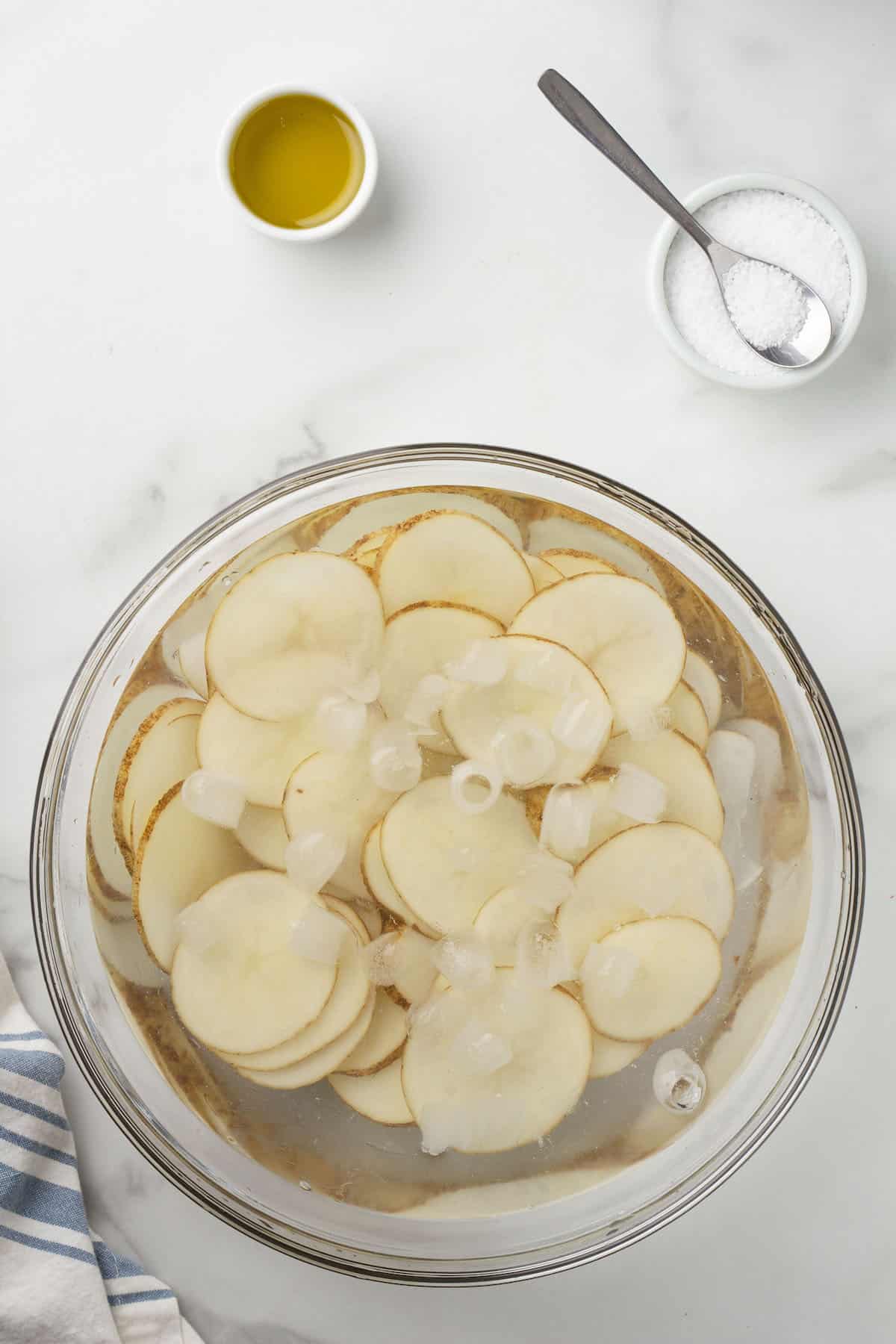 sliced potatoes in a bowl of ice water