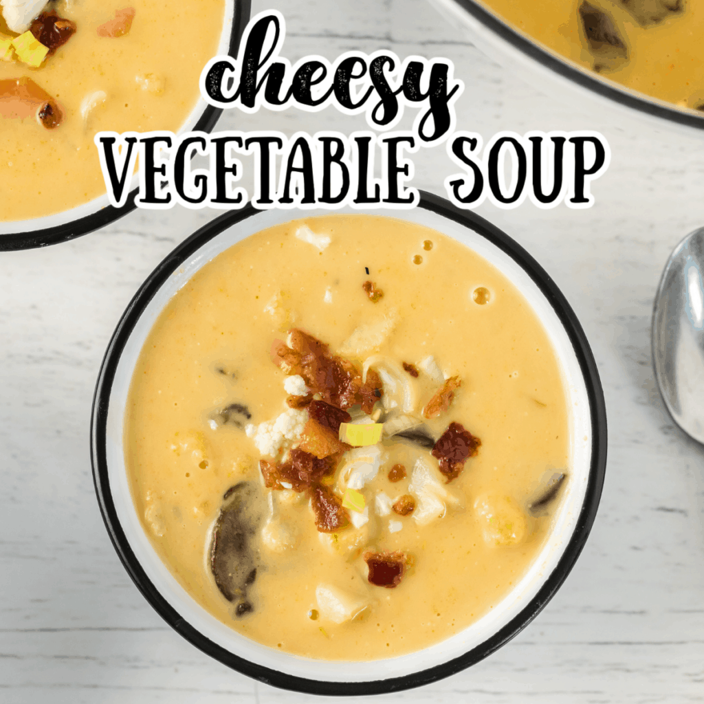 A bowl of creamy cheesy vegetable soup topped with bacon and leeks