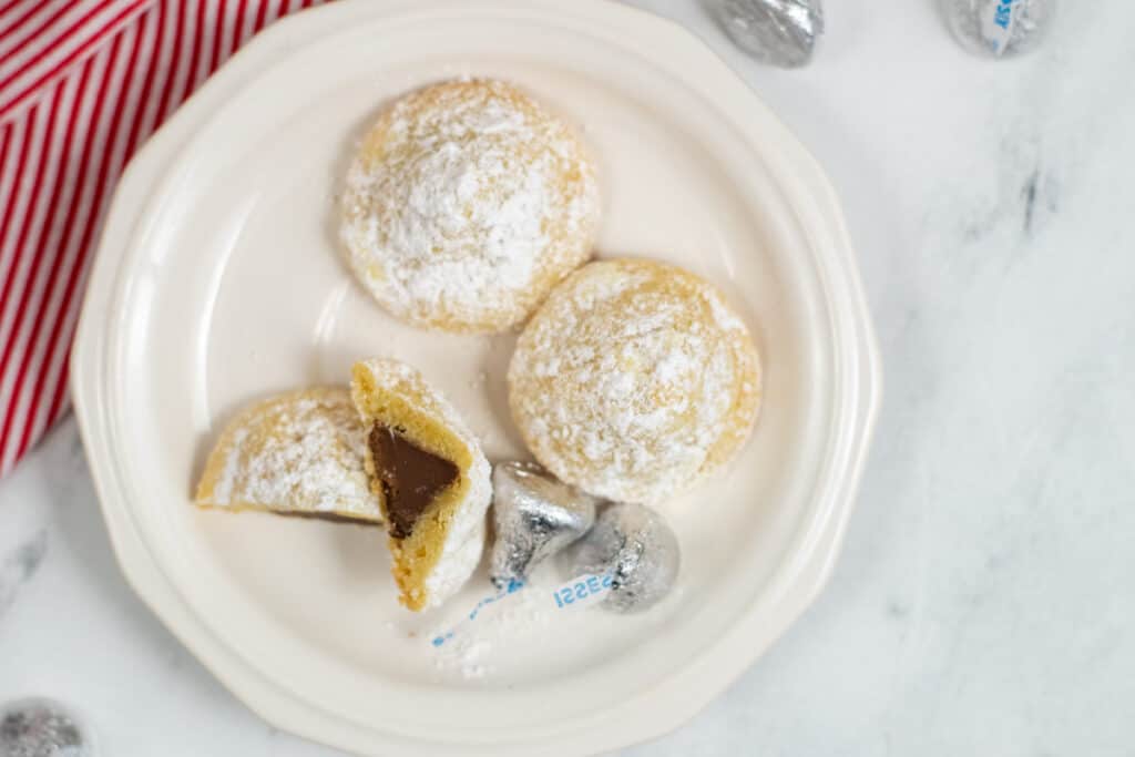 Secret Hershey Kiss cookies on a plate with one cut open to show the kiss inside