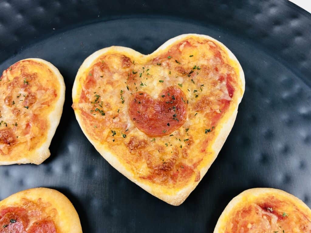 one heart shaped pizza with a heart shaped pepperoni on top