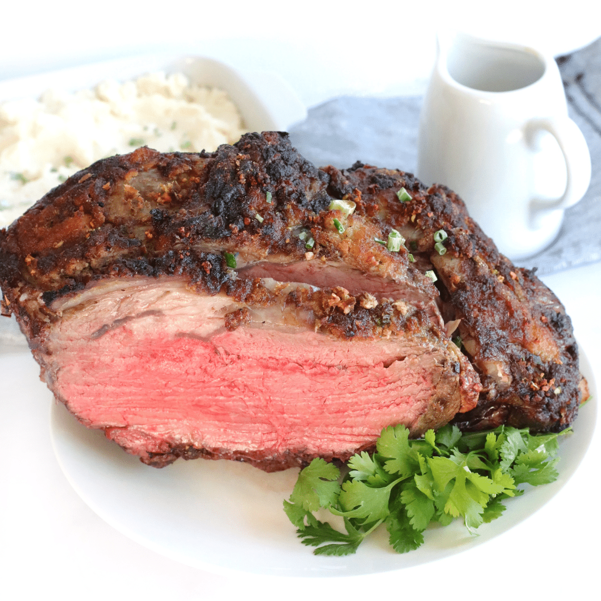 air fryer prime rib cut in half on a white plate with fresh parsley