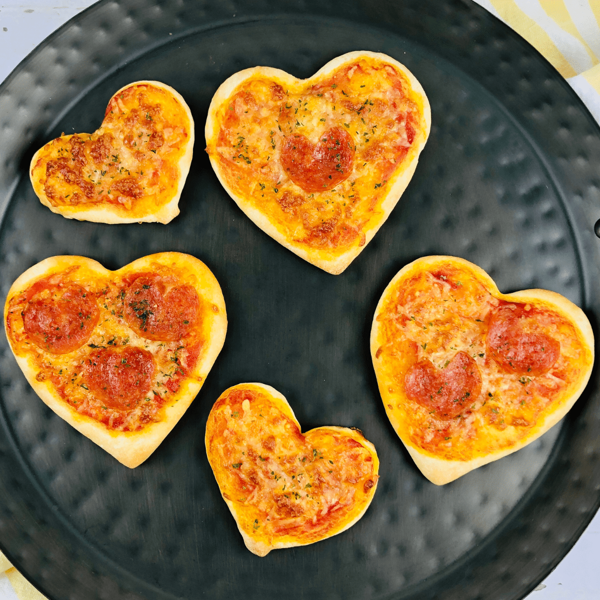 heart-shaped pizzas with heart-shaped pepperoni on a black platter