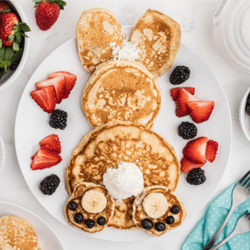 Easter bunny pancakes with fruit and whipped cream on a white plate