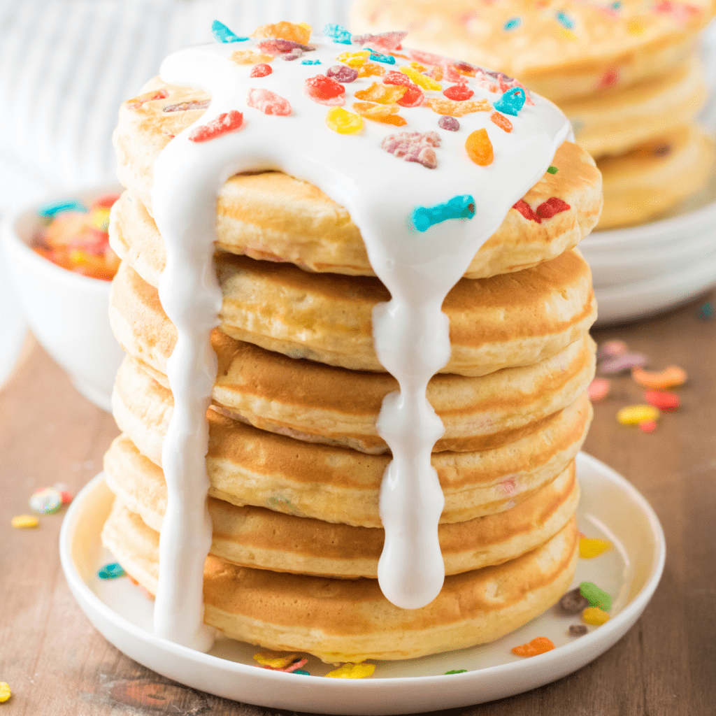 a stack of Fruity Pebbles pancakes topped with marshmallow fluff