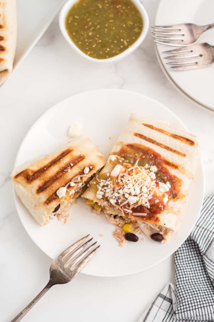 a grilled chicken burrito cut in half on a white plate