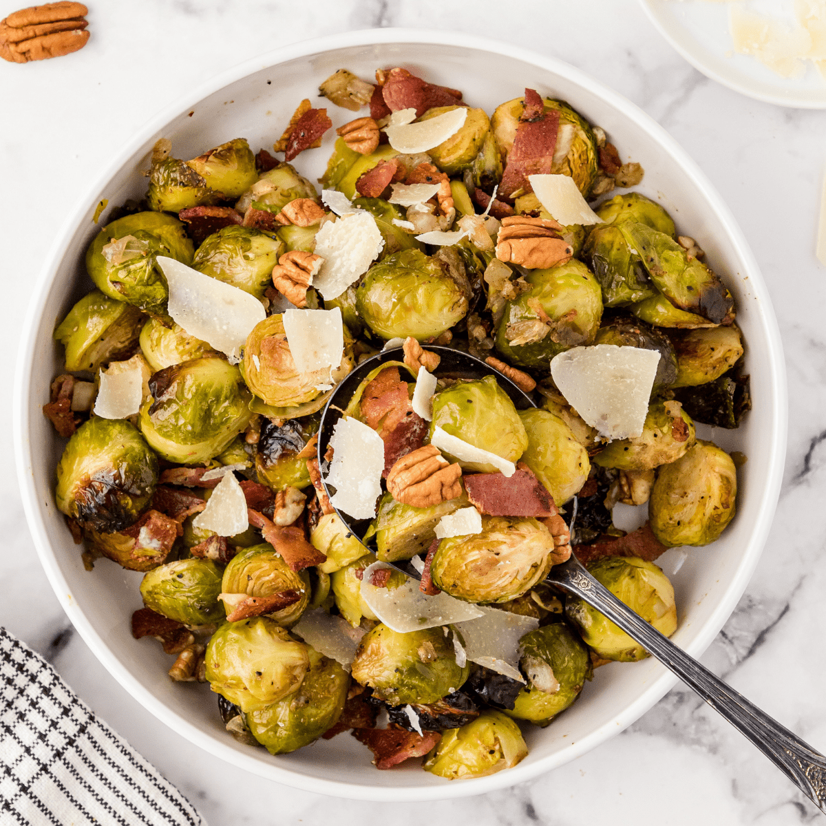 a bowl full of roasted brussels sprouts with bacon, pecans, and Parmesan cheese