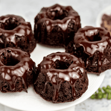 a white plate covered with 5 chocolate brownie bundt cakes, each covered with chocolate ganache