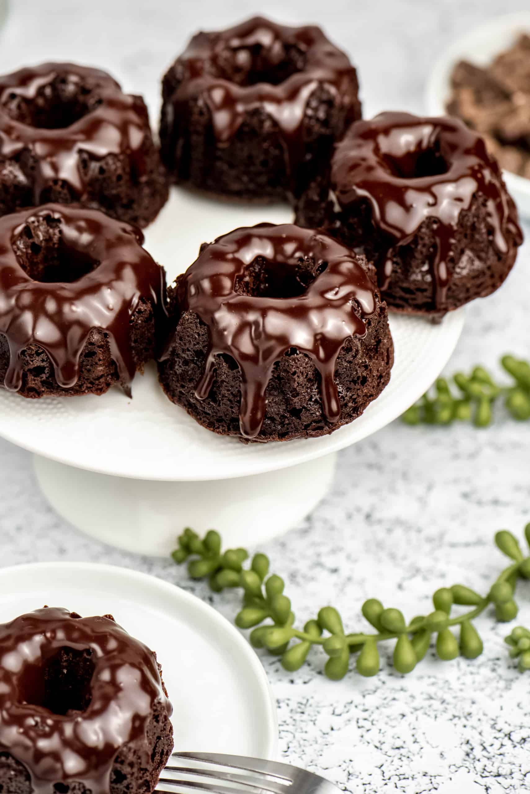 chocolate brownie bundt cakes with chocolate ganache on top, sitting on a cake plate