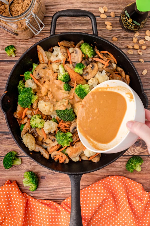pour the peanut stir fry sauce over the chicken and veggies in the skillet