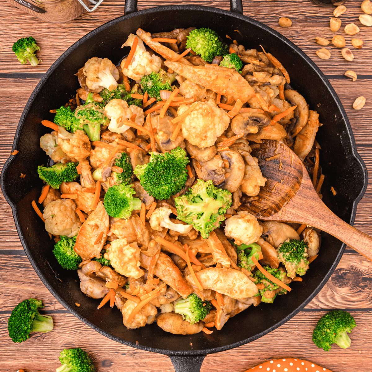 peanut stir fry sauce over chicken and vegetables in a cast iron skillet