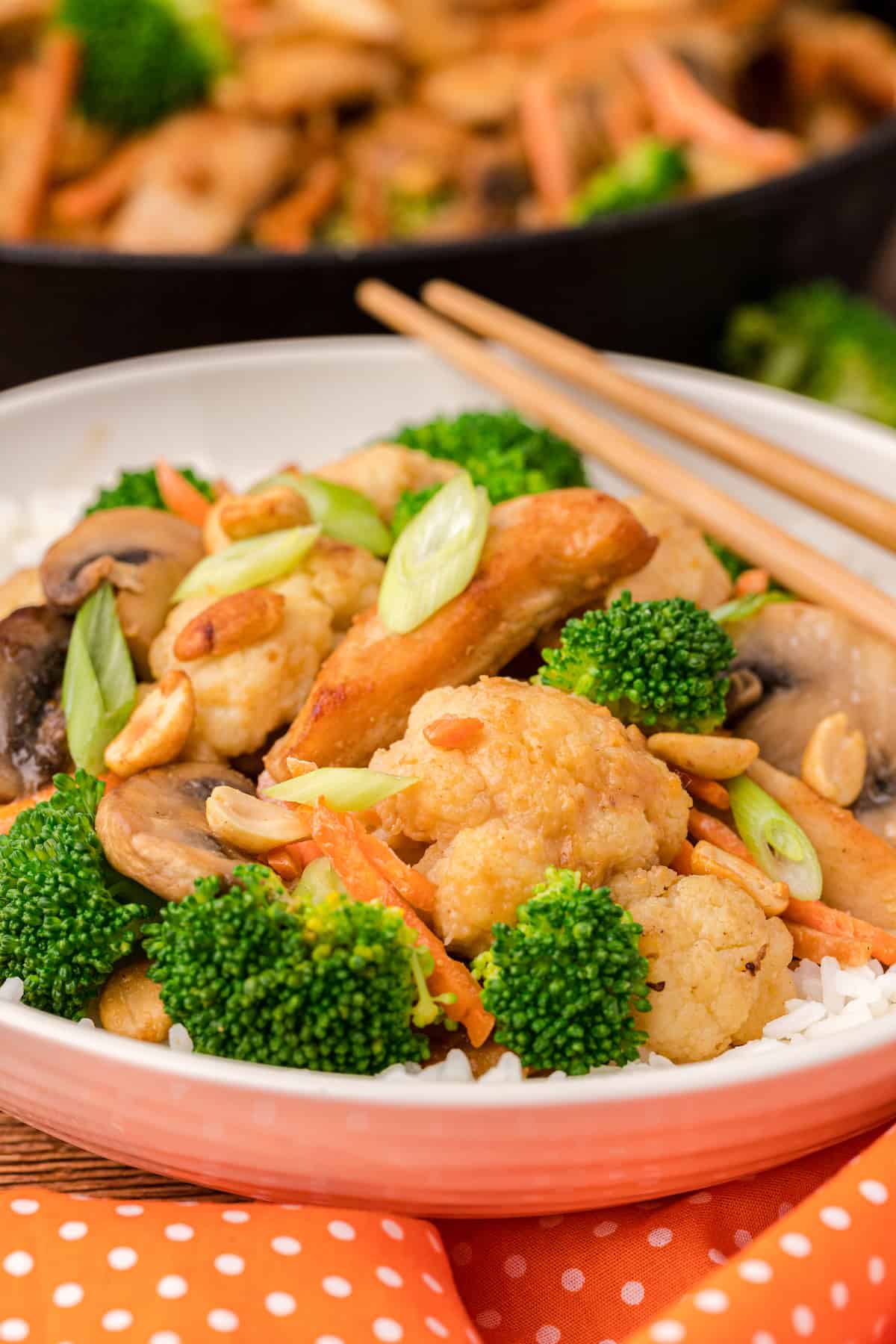 a close up of peanut stir fry on a white plate with chopsticks