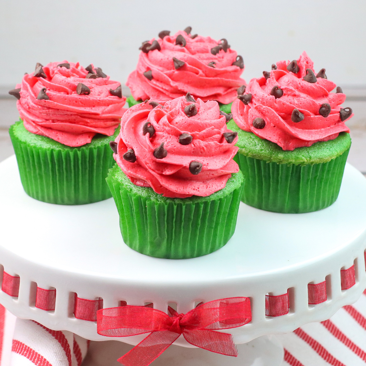 a tray of watermelon cupcakes with chocolate chip seeds