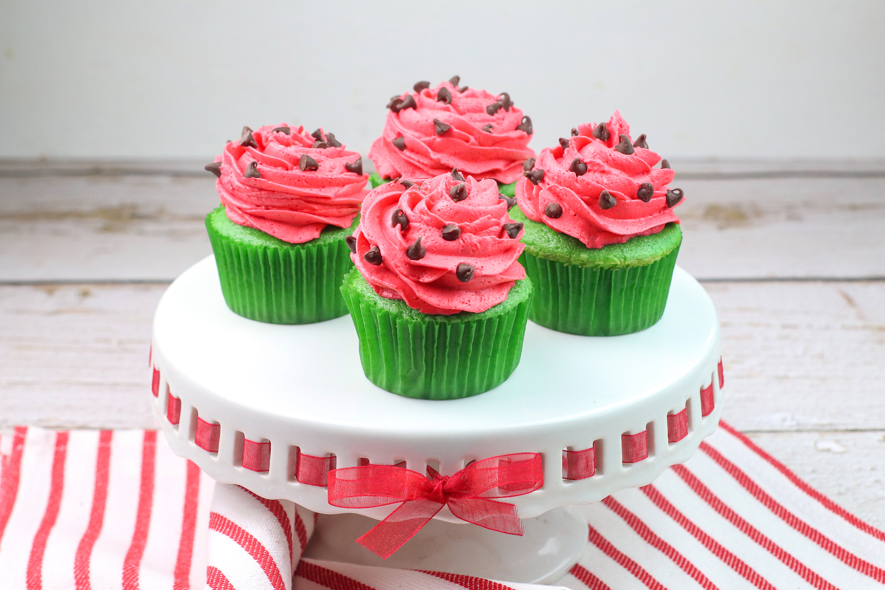 a tray of watermelon cupcakes with watermelon frosting