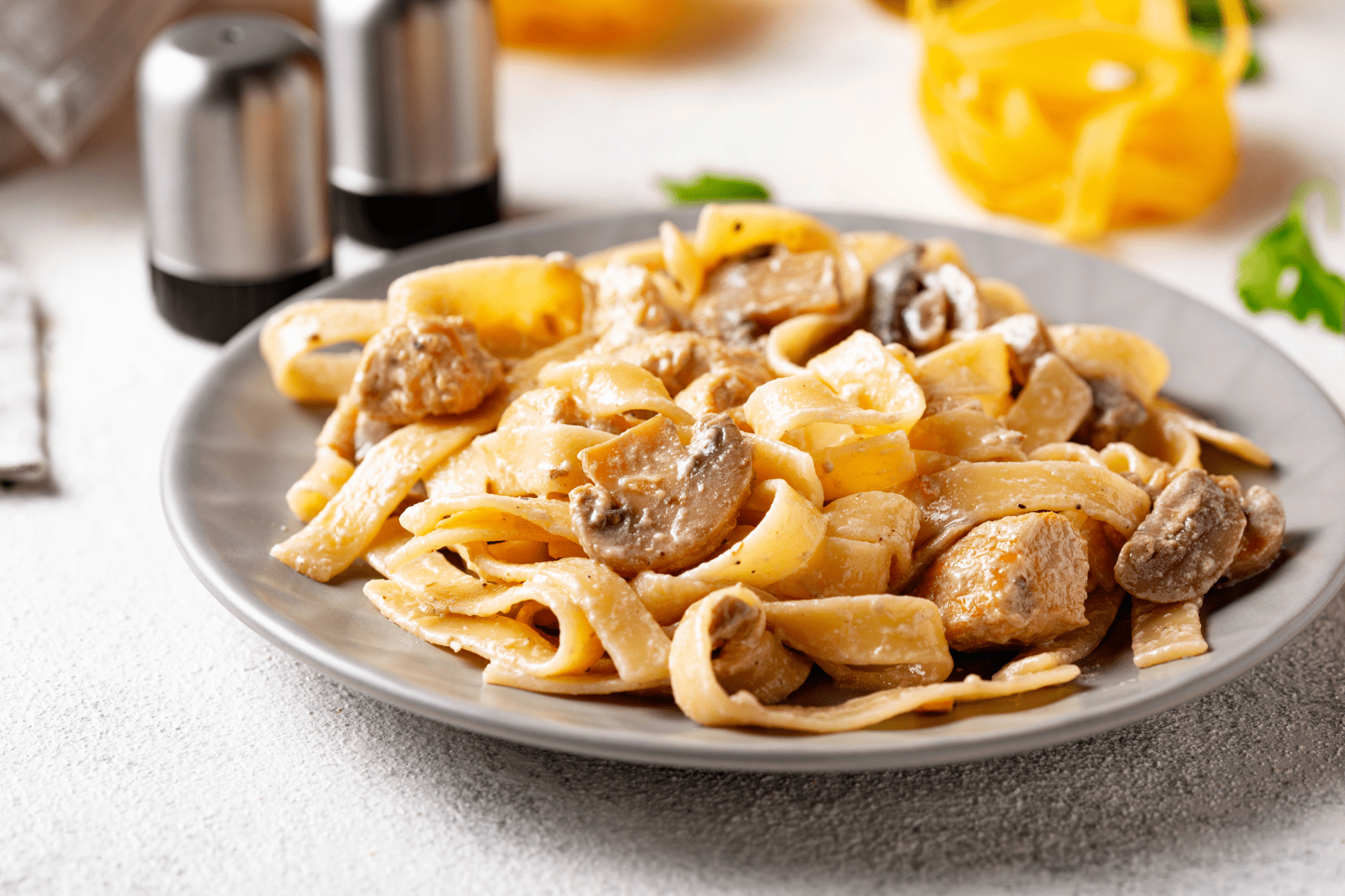 balsamic chicken and mushrooms over noodles on a gray plate