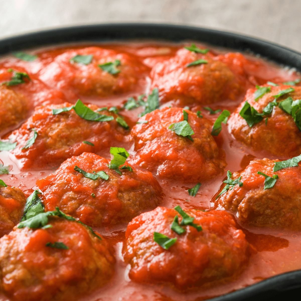 cheesy meatballs with spaghetti sauce in a cast iron skillet