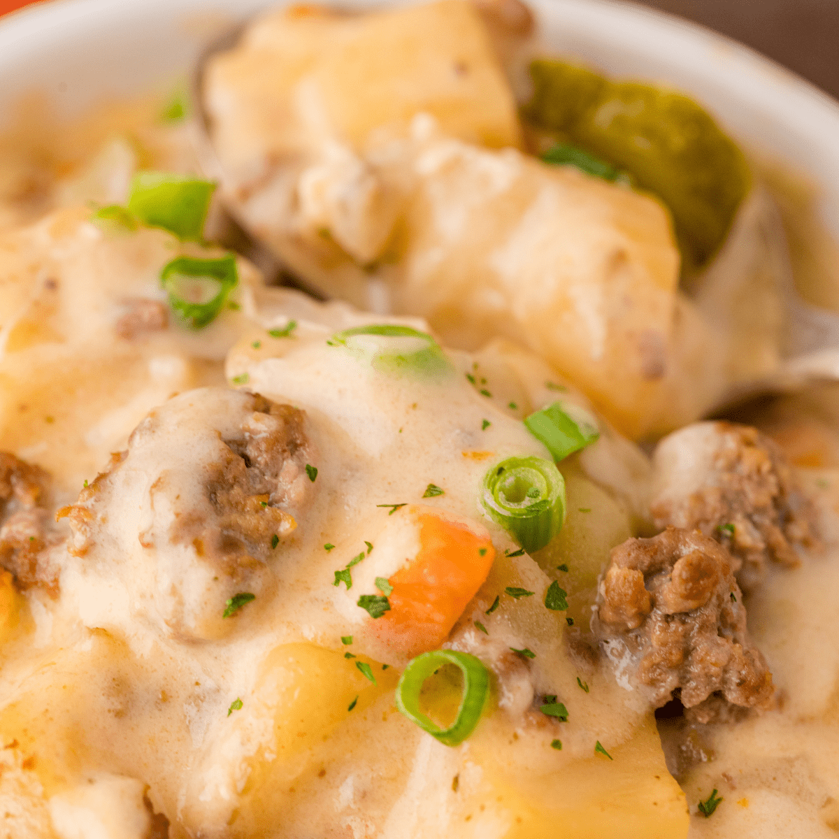 a close up of Crockpot cheeseburger soup in a white bowl