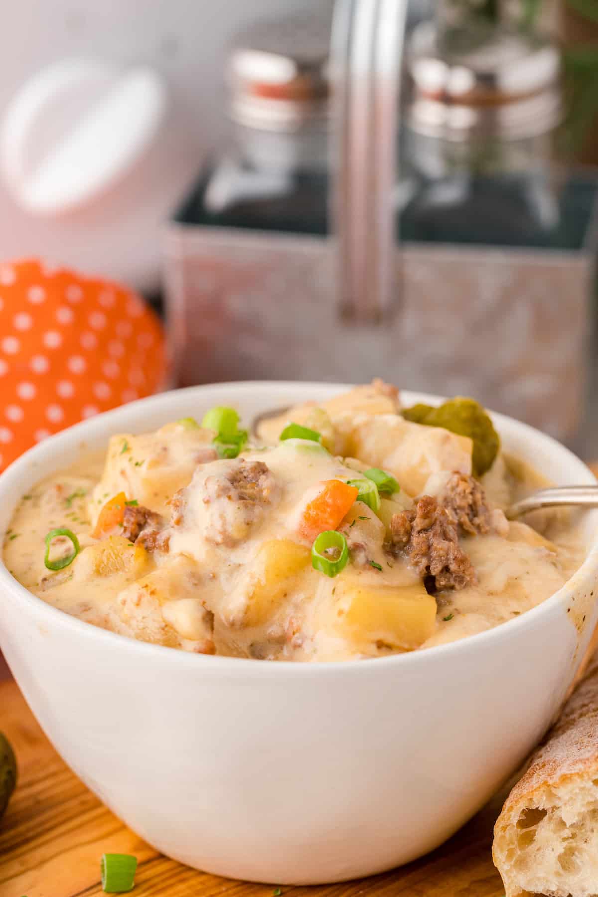 a bowl full of cheeseburger soup with the slow cooker in the background