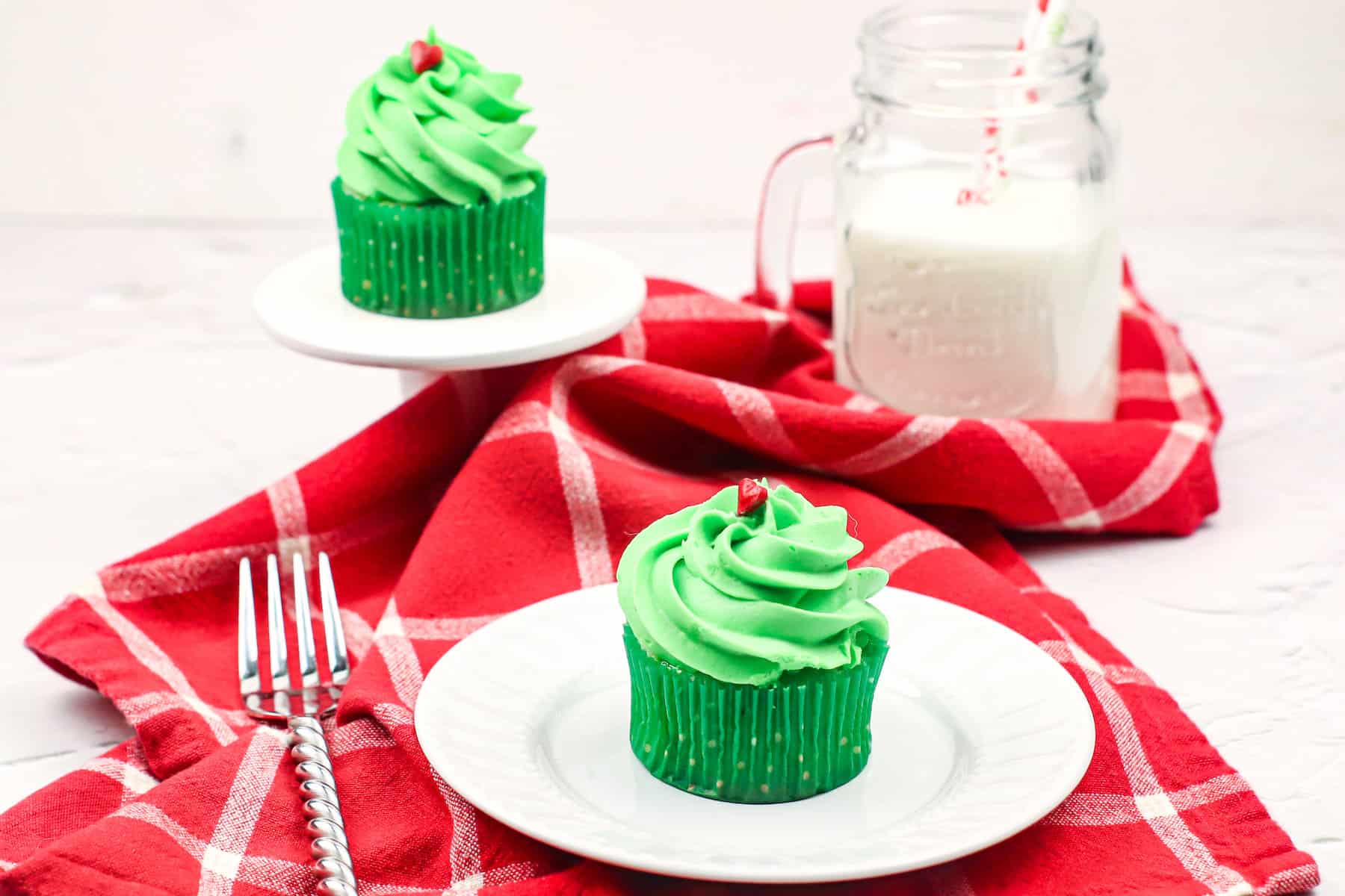 one Grinch pistachio flavored cupcake on a white plate on top of a red napkin