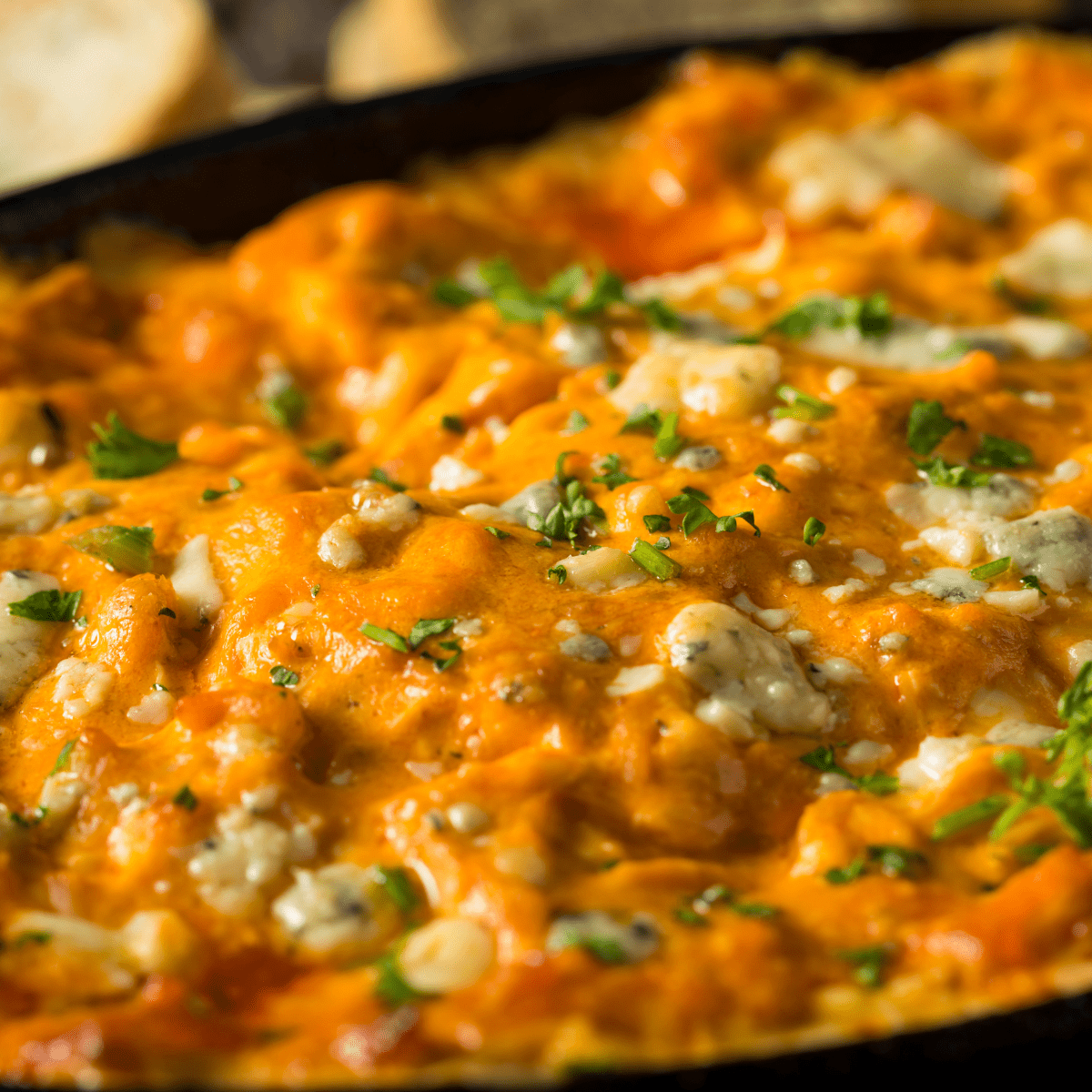 a closeup of buffalo chicken dip in a black cast iron skillet