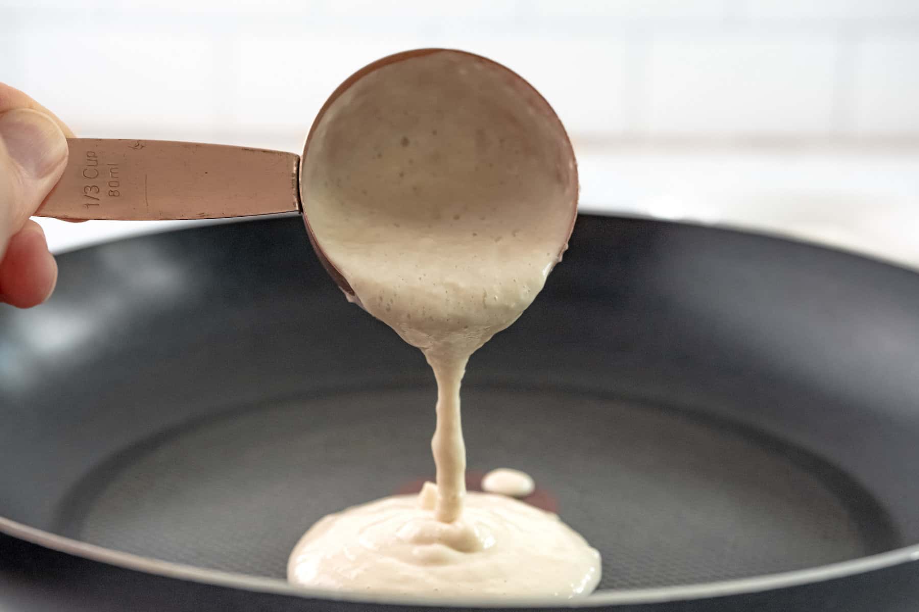 pouring pancake batter into a skillet