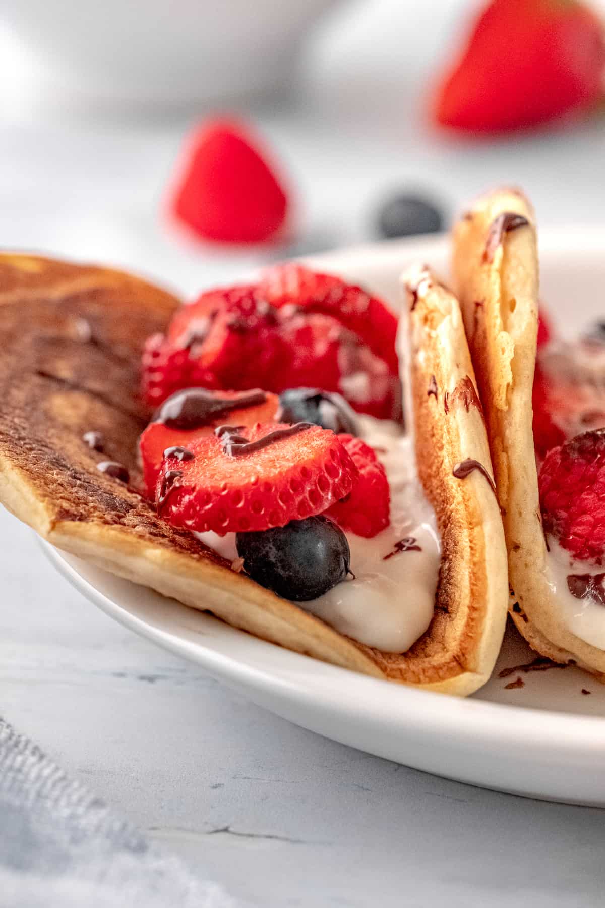 a close up of a pancake taco with Greek yogurt, strawberries, blueberries, and raspberries