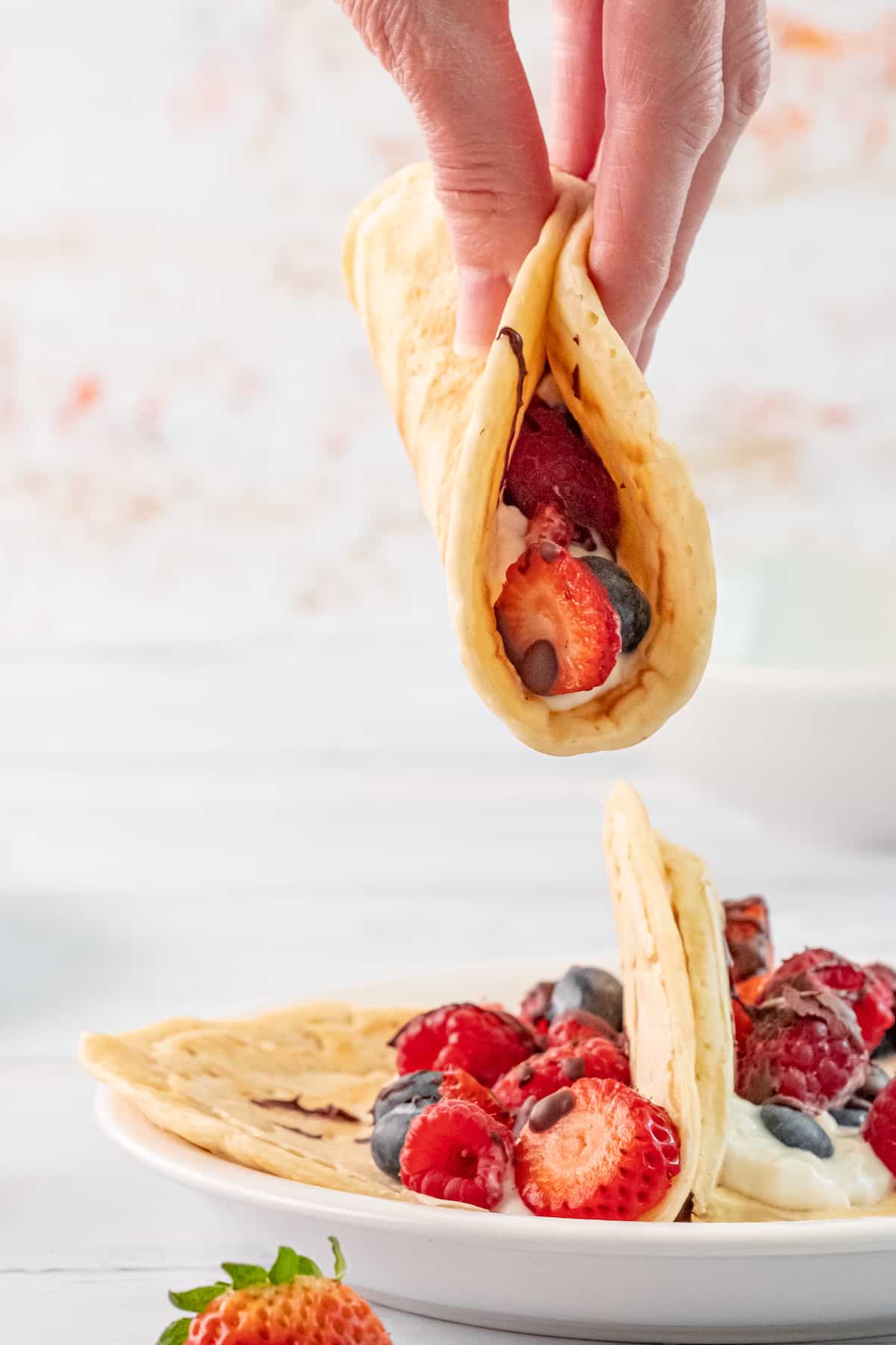 one pancake taco above a plate of fruit tacos