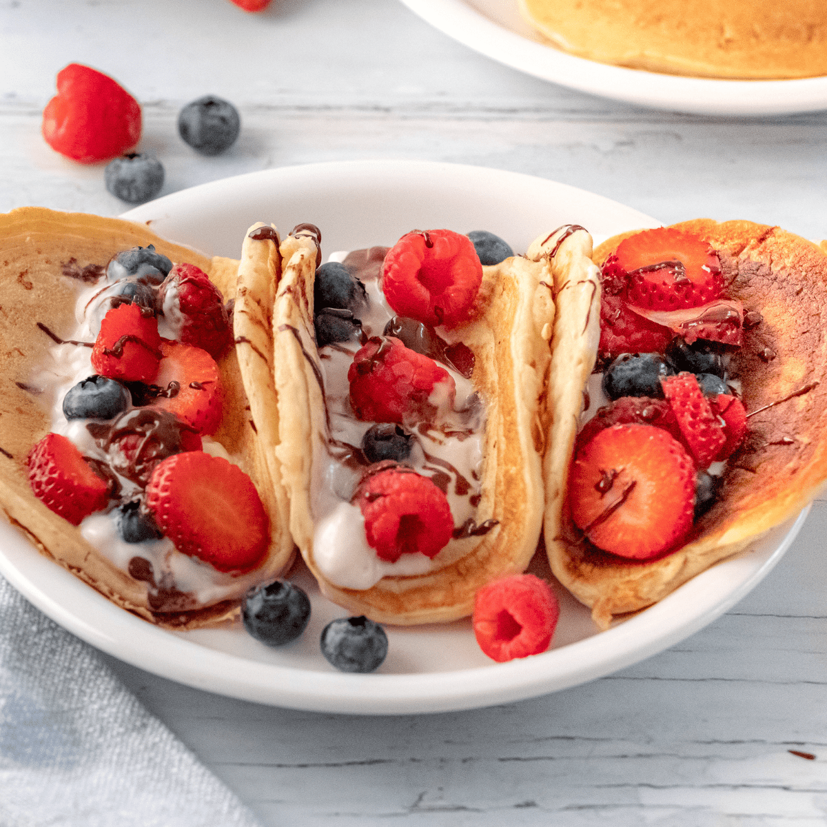 three pancake fruit tacos on a white plate