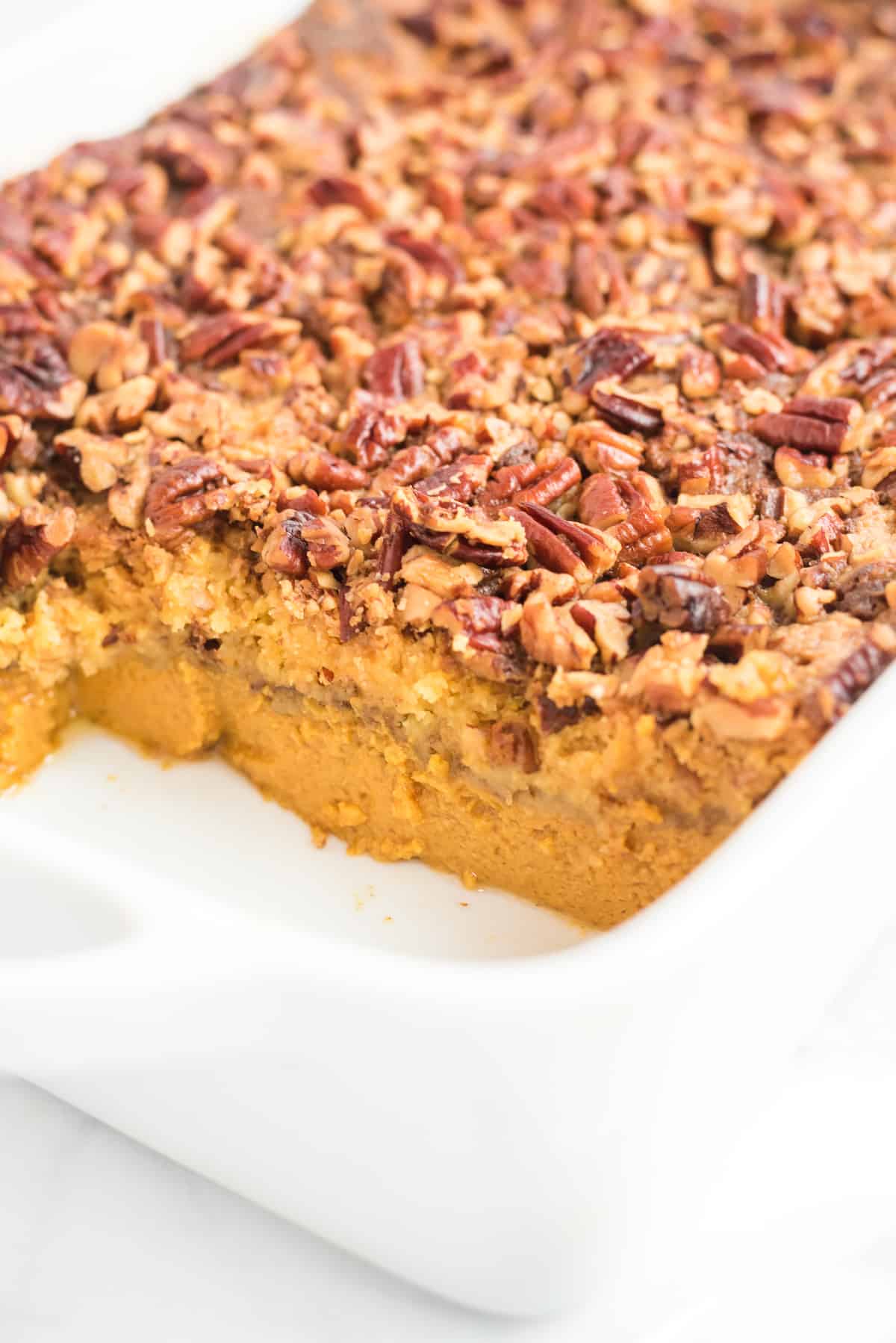 pumpkin dump cake with a slice taken out in a white cake pan