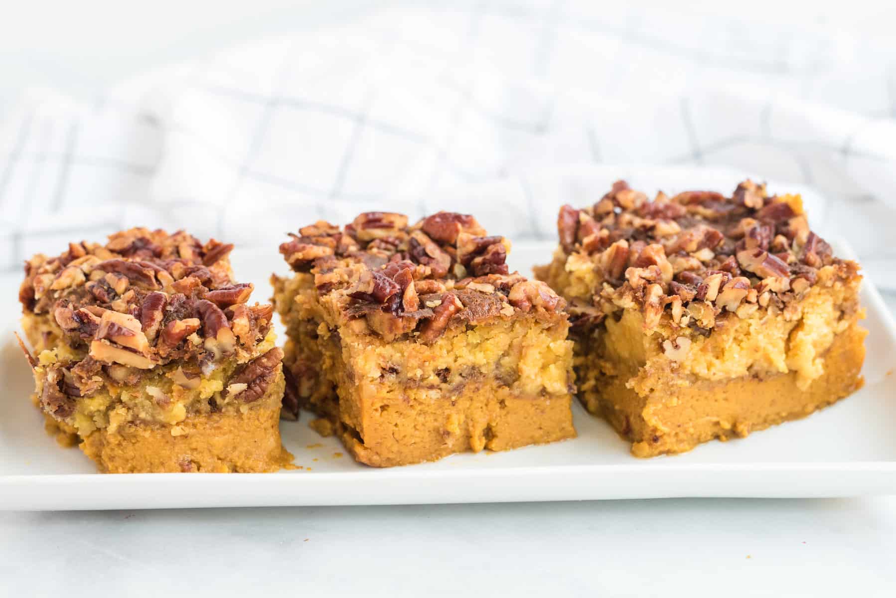 three slices of pumpkin dump cake on a white tray