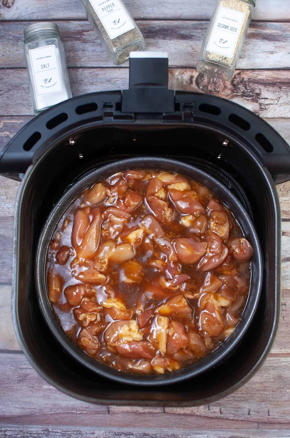 pour the chicken and marinade into a cake pan and place inside the air fryer basket