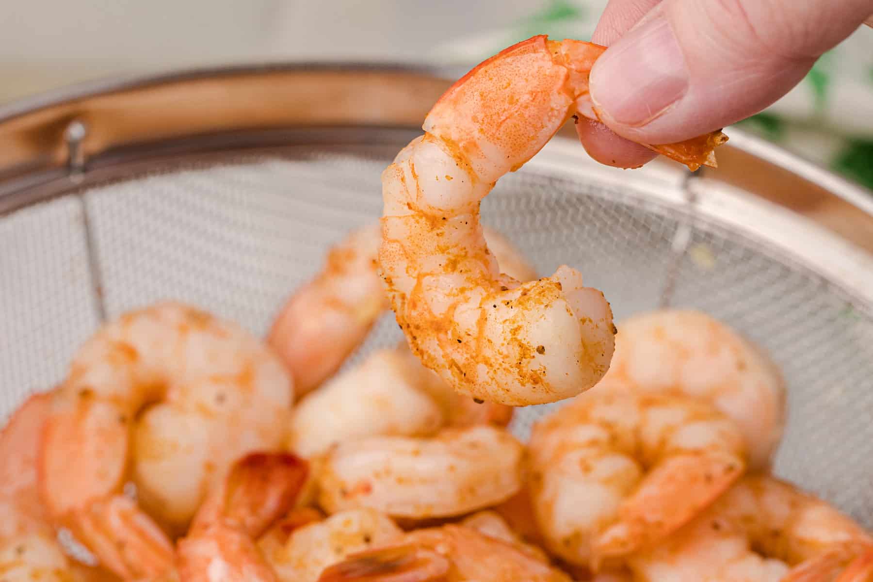 Old Bay Steamed Shrimp behind held in fingers