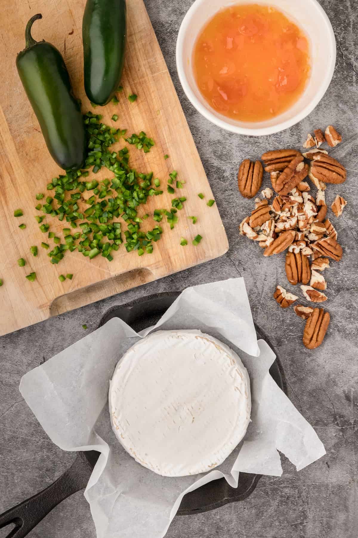 baked brie ingredients including apricot jam, pecans, and jalapeño peppers