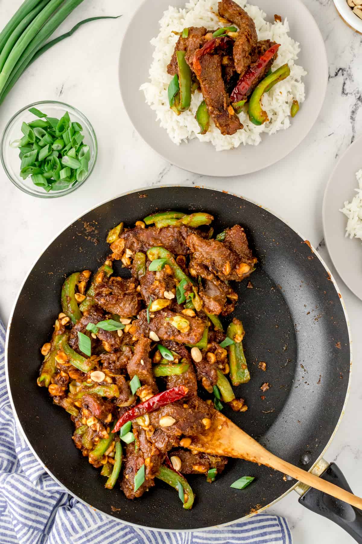 a skillet of Kung Pao beef and a single serving on a white plate