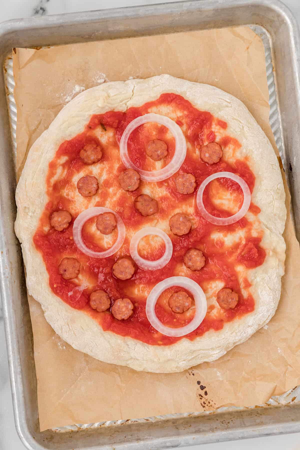 top the homemade pizza dough with sauce and toppings such as pepperoni and onions