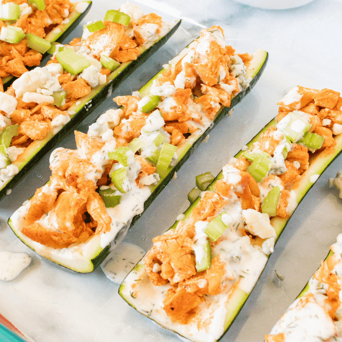 Buffalo Chicken Zucchini Boats with blue cheese crumbles, diced celery, and homemade ranch dressing
