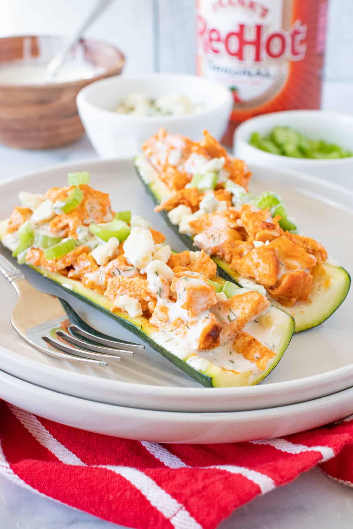 Buffalo Chicken Zucchini Boats on a white plate with a red napkin